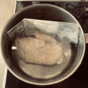 沸騰したお湯に、玉ねぎ麹がなじんだ鶏胸肉を入れ、弱火で５分煮ている様子。