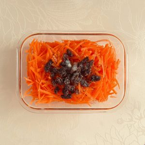 保存容器に、塩麹、オリーブオイル、バルサミコ酢、レーズン、ブラックペッパーが加えられた様子