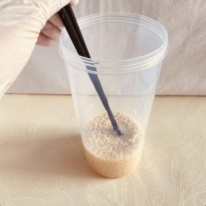 容器に、冷凍生麹、塩、水を入れ、さえばしで混ぜるている様子