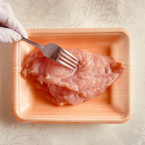 フォークで鶏胸肉全体に穴をあけている様子