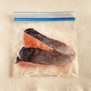 生鮭切り身２切がチャック付きポリ袋に入れられ、塩麹大さじ１が全体的にまぶされた様子
